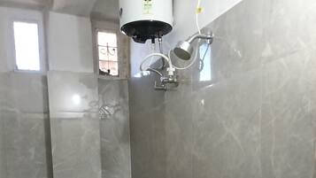 A bathroom with a toilet, bidet, sink, and a red bucket on the floor.