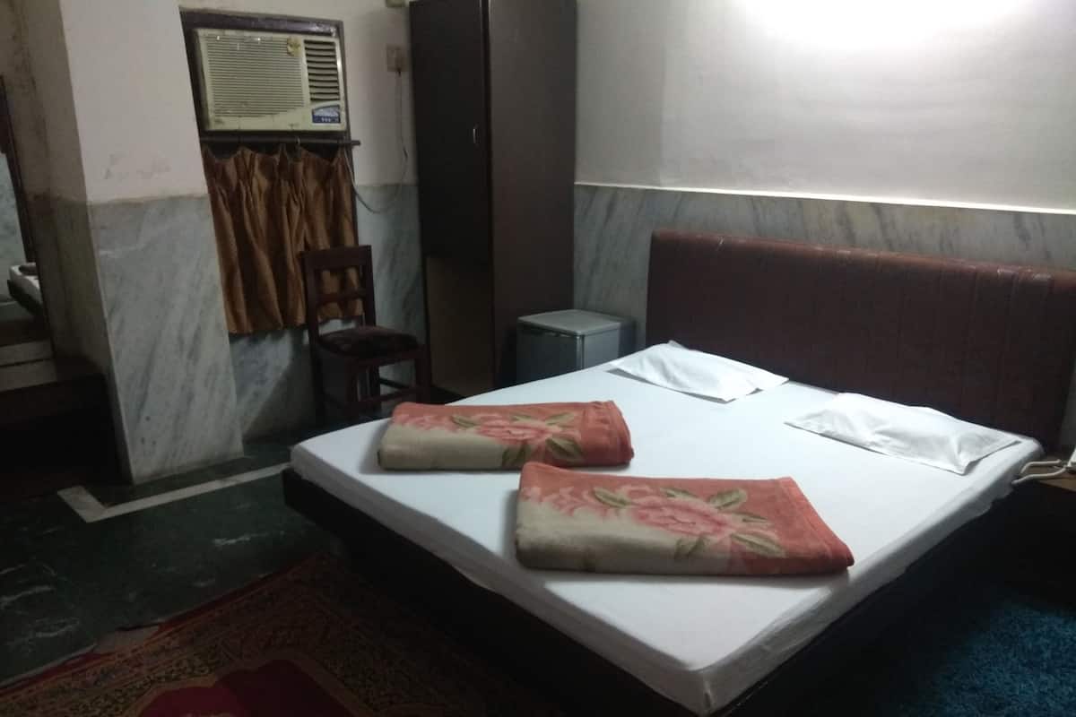 Ein Hotelzimmer mit einem Bett, einem Sessel, einem kleinen Tisch und einer Klimaanlage.