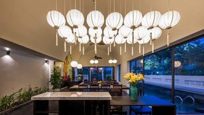 Een modern interieur met een bar, hangende lantaarns en uitzicht op buiten.