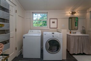 A laundry room with two washing machines, a window, a framed picture, a sink, and a mirror. - Horseshoe Hollow, Private Log Cabin on 10 acres (Lake Toxaway)