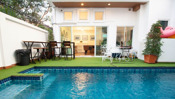 Piscina com área de terraço, incluindo cadeiras e mesa.