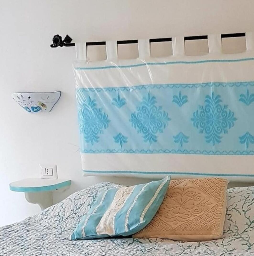 A bedroom with a bed, a nightstand, and a wall-mounted shelf.