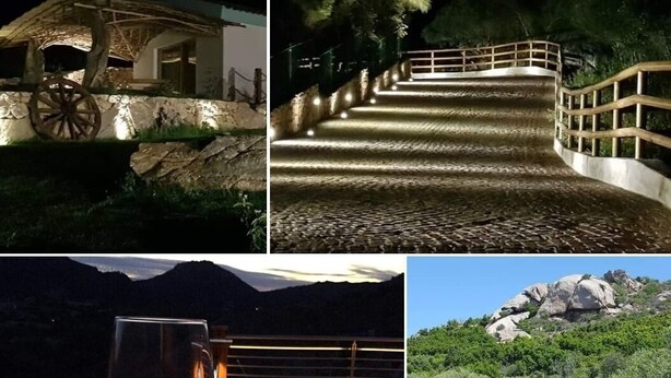 A rustic building with a large wooden wheel, a stone wall, and a wooden deck. - Petra manna summer Palau Sardinia  (PALAU)