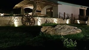 A rustic building with a stone wall, a large wooden wheel, and a thatched roof structure. - Petra manna summer Palau Sardinia  (PALAU)