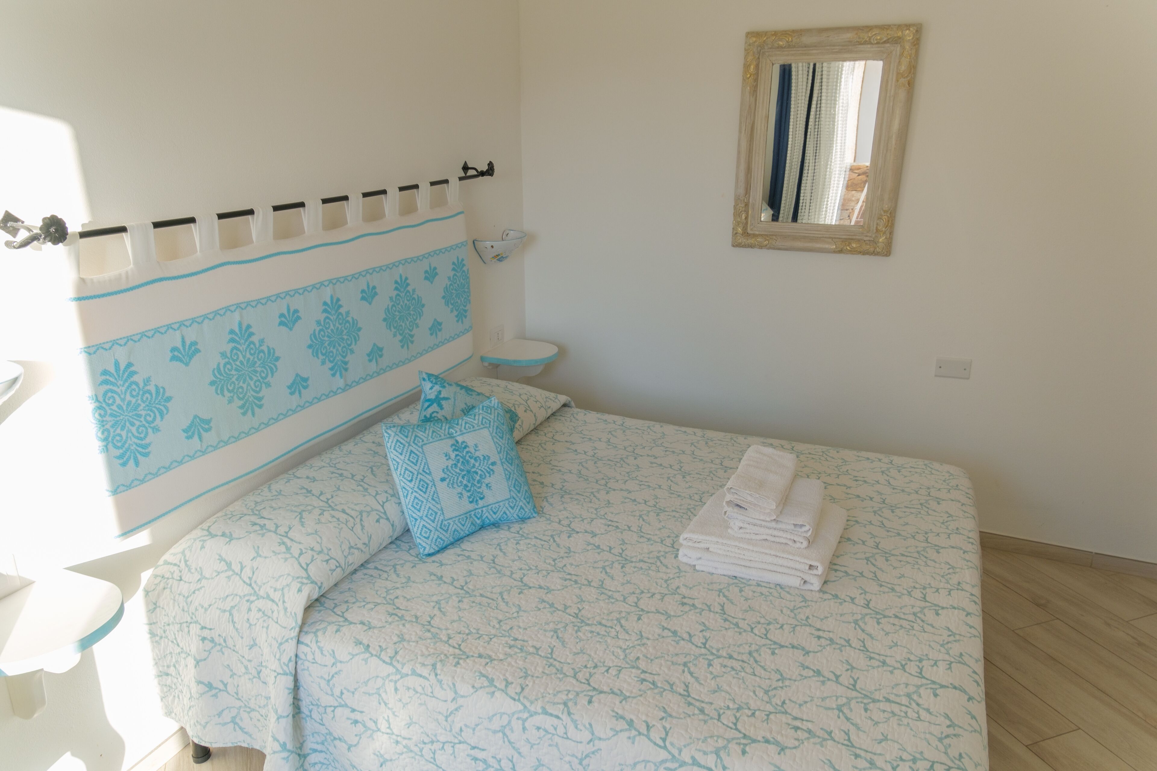 Ein Schlafzimmer mit Bett, Nachttisch, Wandspiegel und Toilette.