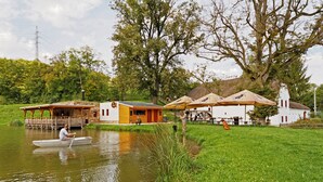 A riverside property with a small dock, a boat, and a building with a red roof.