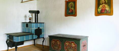A room with a wooden table, a green cabinet with floral designs, and two framed religious paintings on the wall.