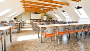 A conference room with multiple tables and chairs, wooden beams on the ceiling, and skylights.
