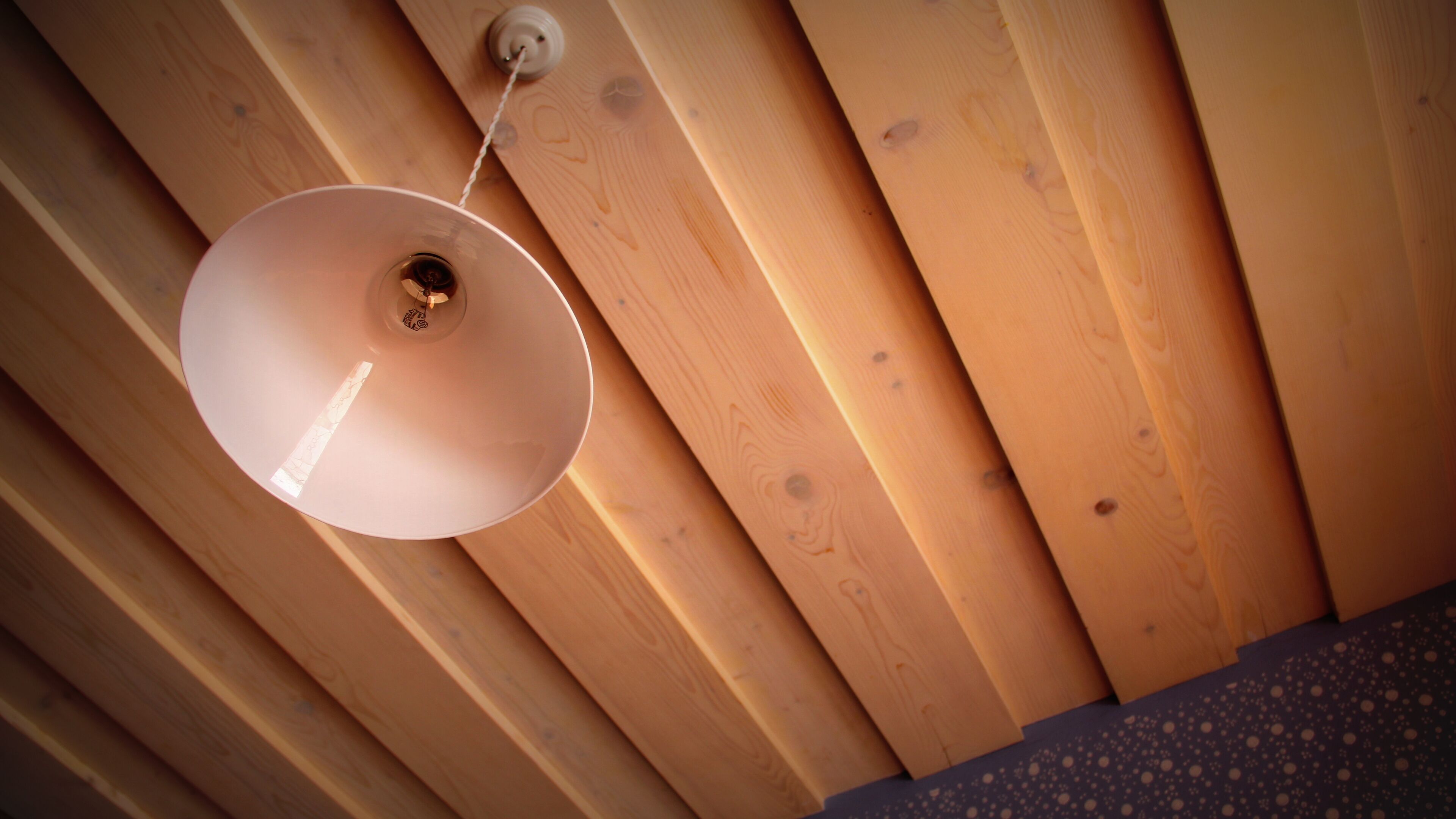 A ceiling with wooden slats and a hanging light fixture.