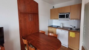 A compact kitchen with wooden cabinets, a microwave, a sink, and a dishwasher. - Studio cabin - 4 guests, calm close to slopes (La Mongie)