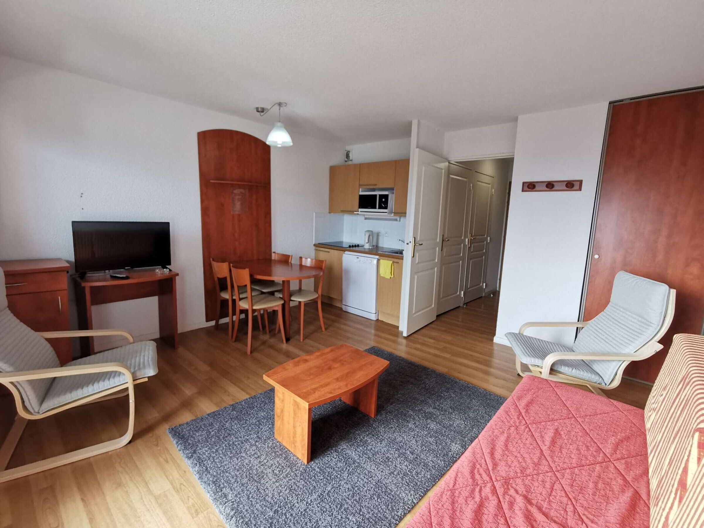Ett kompakt bostadsutrymme med en matplats, ett litet kök och en sittgrupp.