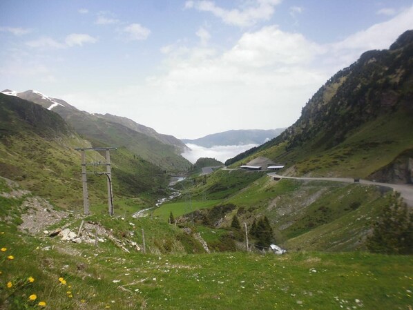 A mountainous landscape with a winding road, a river, and a building with a flat roof.
