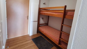 A room with a wooden bunk bed, a door, and a small rug on the floor. - Studio cabin - 4 guests, calm close to slopes (La Mongie)