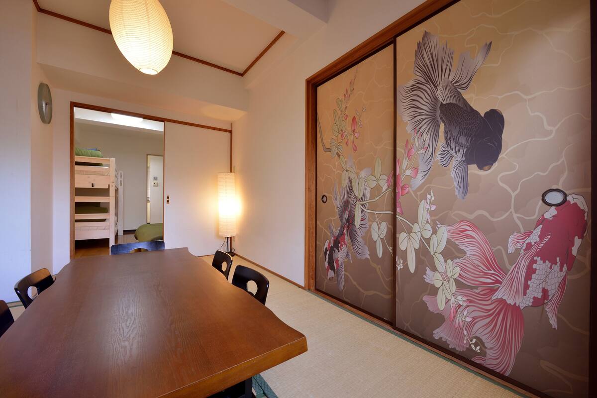 A traditional Japanese room with tatami flooring, a wooden table, and a sliding door with a koi fish mural.