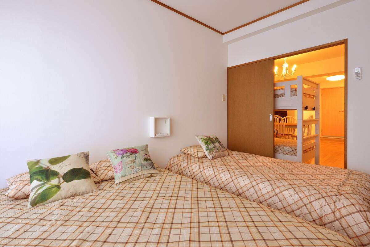 A bedroom with two beds, a small bedside table, and a wardrobe.