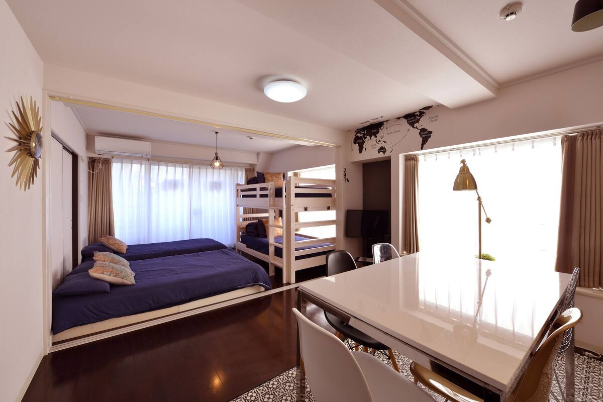 A compact room with bunk beds, a dining table, and a world map on the wall.