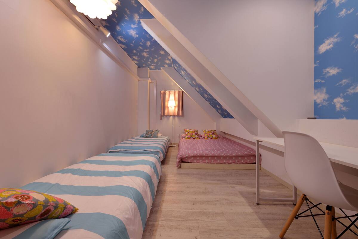 A bedroom with two beds, a desk, and a chair.