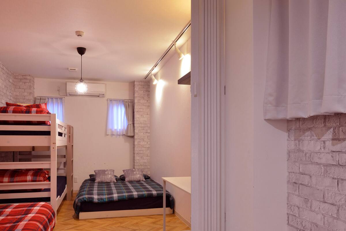 A dormitory room with bunk beds, a single bed, and a desk.