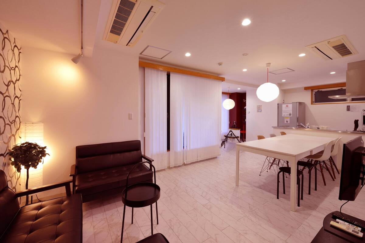 A modern living room with a sofa, a coffee table, and a dining area with a table and chairs.