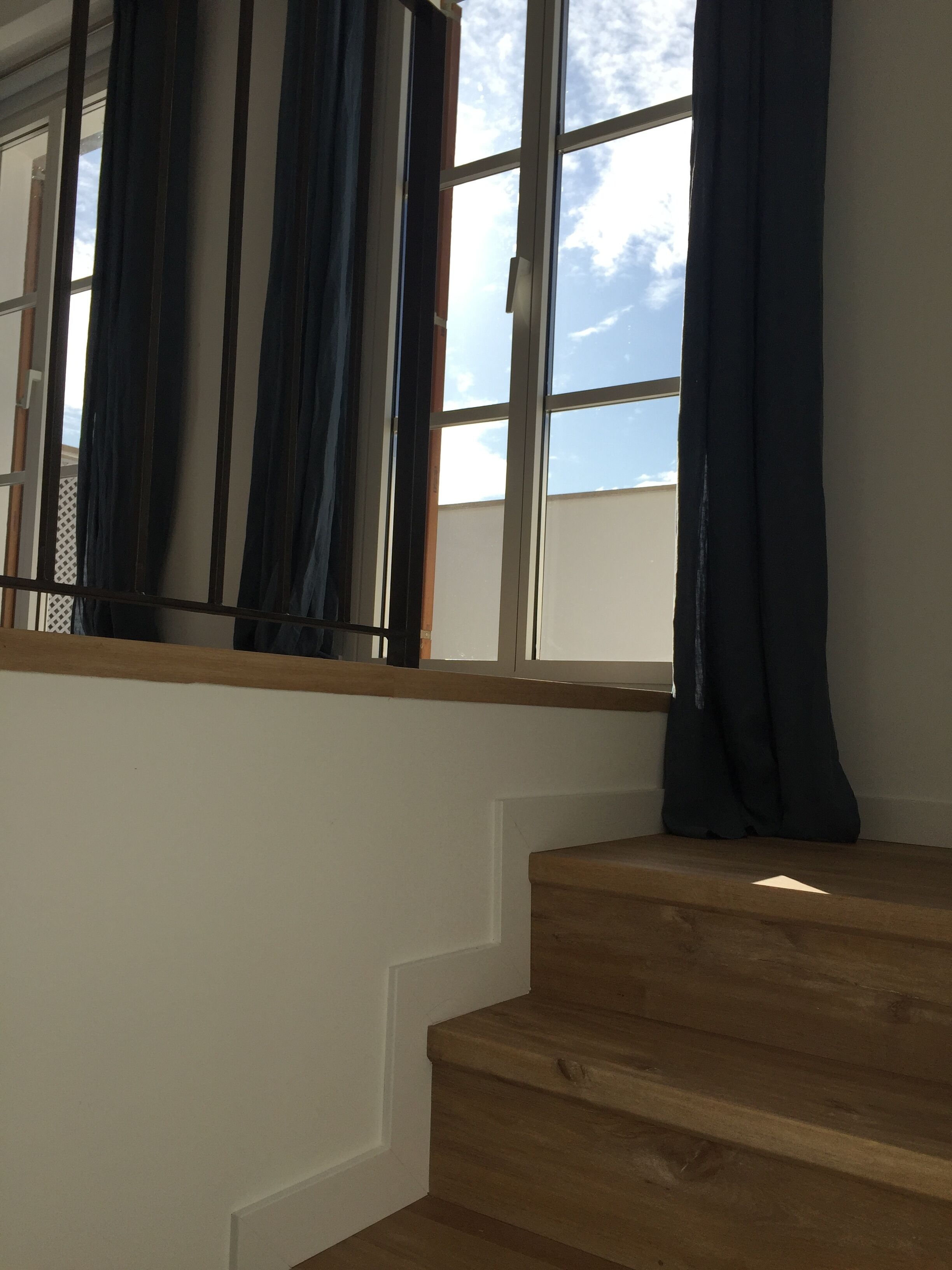 A staircase with wooden steps and a window with curtains.