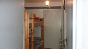 Una stanza piccola e stretta con un letto a castello, una porta e un piccolo armadio.
