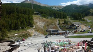 Un rifugio alpino con una seggiovia, posti a sedere all'aperto e vista sulla foresta circostante.