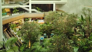 A multi-level atrium with indoor plants, seating areas, and a central display. - Grand Josun Jeju (Seogwipo)