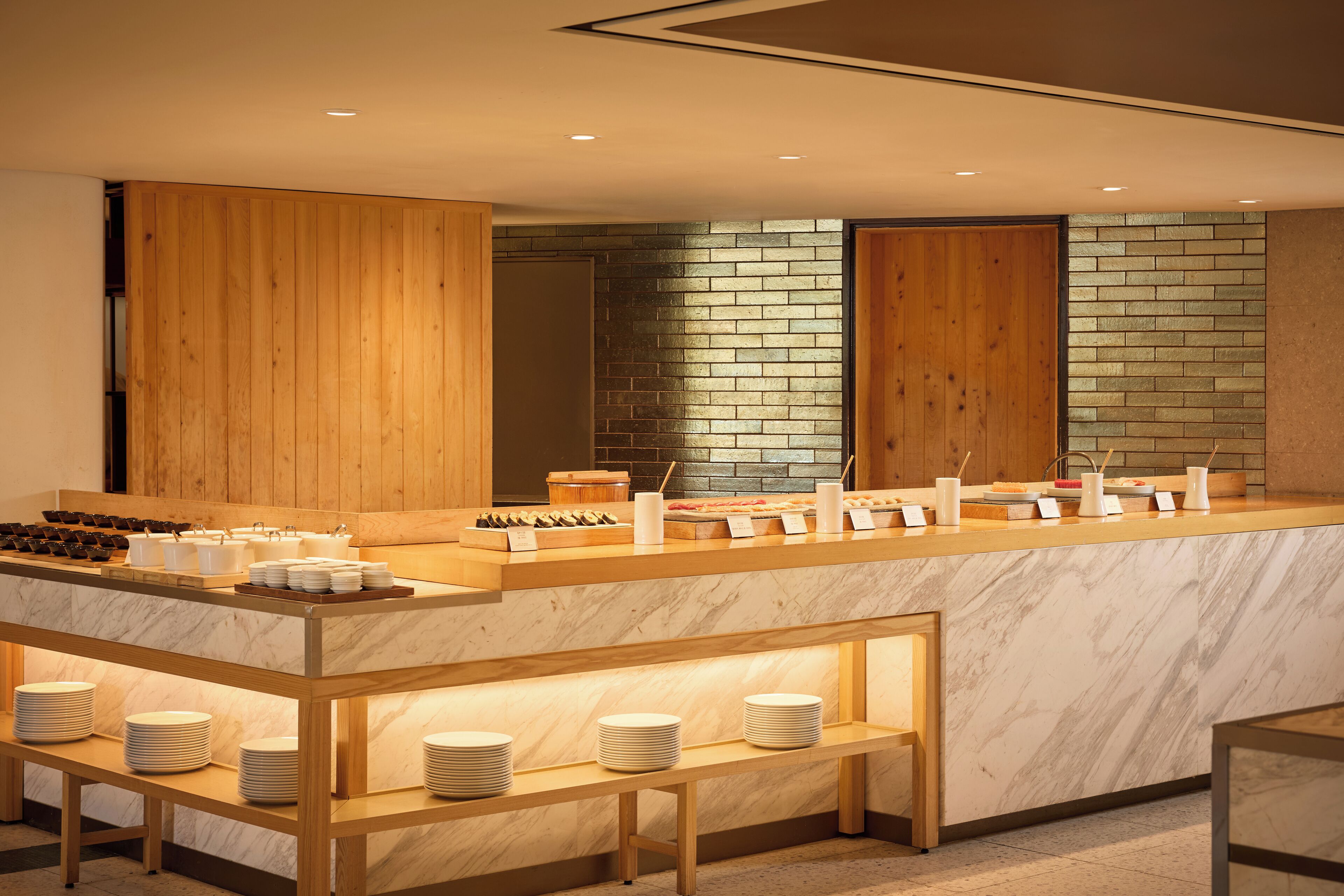 A modern breakfast bar with marble countertops and wooden accents, featuring a variety of breakfast items and utensils.