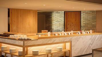 A modern breakfast bar with marble countertops and wooden accents, featuring a variety of breakfast items and utensils.