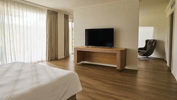 Habitación de hotel con una cama grande, un escritorio de madera y un televisor de pantalla plana, además de una silla de masaje.