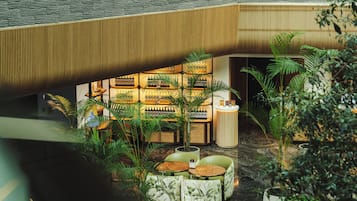An indoor area with seating, plants, and a bar with bottles.