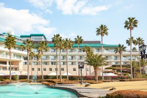 A hotel with a pool, palm trees, and a well-maintained garden. - Grand Josun Jeju (Seogwipo)