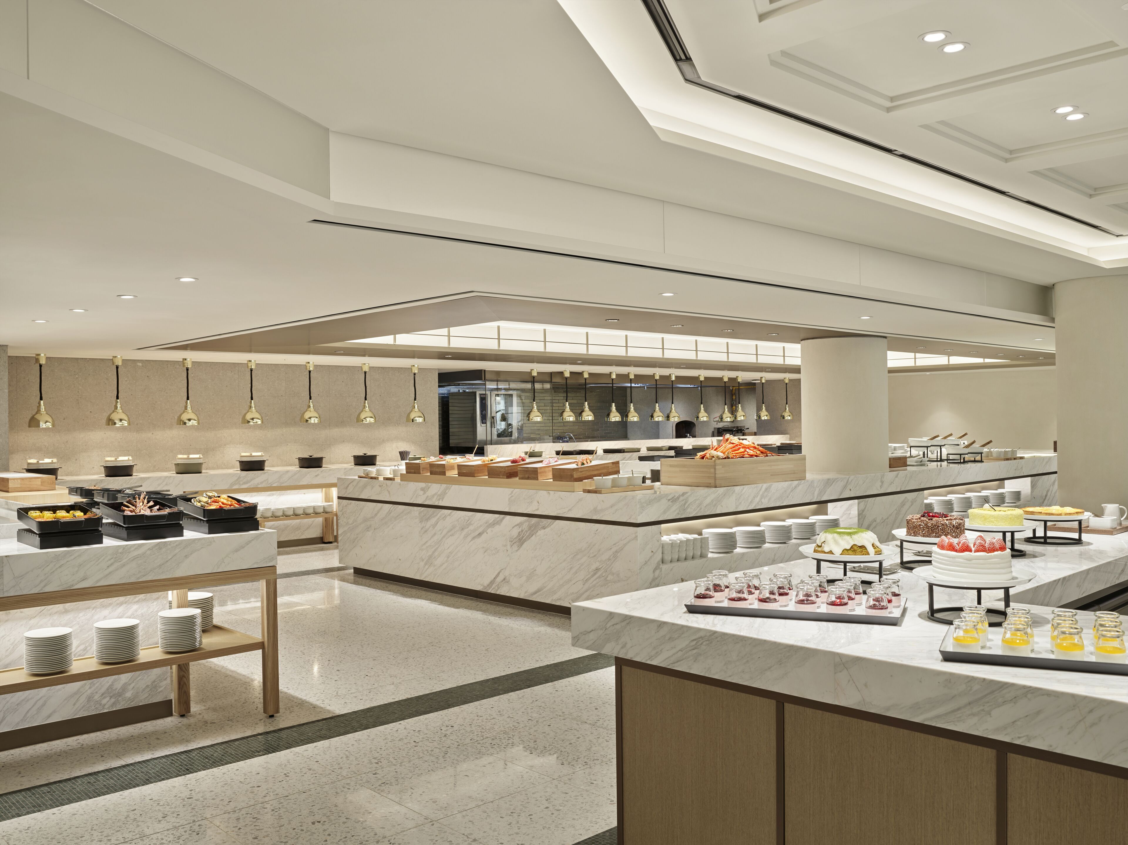 A modern hotel lobby with a spacious layout, a central reception area, and a buffet setup with various food items.