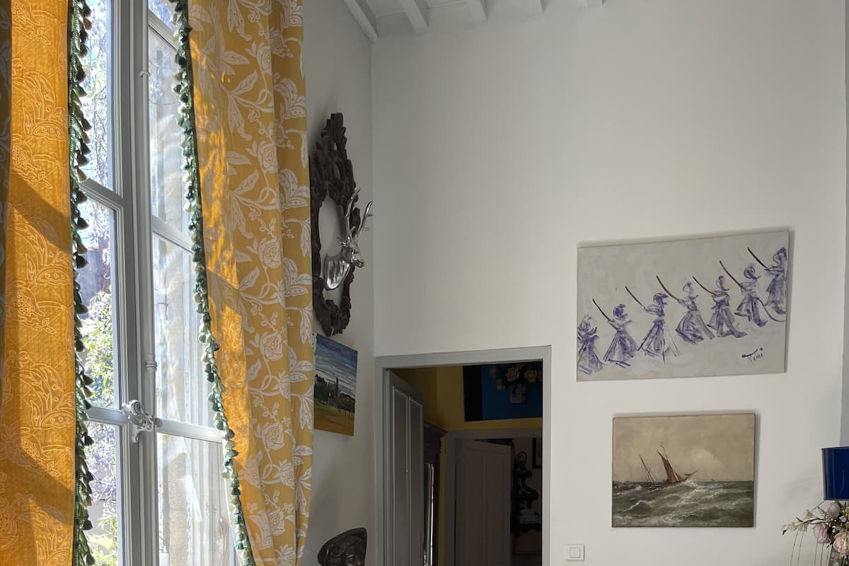 A room with two ornate chairs, a radiator, and artwork on the walls.