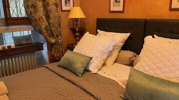 Ein Schlafzimmer mit einem Bett, Kissen, einem Nachttisch, einer Lampe und gerahmten Bildern an der Wand.