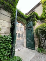Una puerta verde con diseño clásico, ubicada en un edificio de piedra con una entrada arqueada.