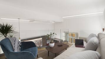 A modern living room with a sofa, armchair, coffee table, and a laptop on the table.