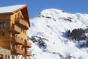 A wooden mountain lodge with balconies overlooking a snow-covered mountain. - Résidence Odalys Rochebrune Les Cimes (Orcieres)