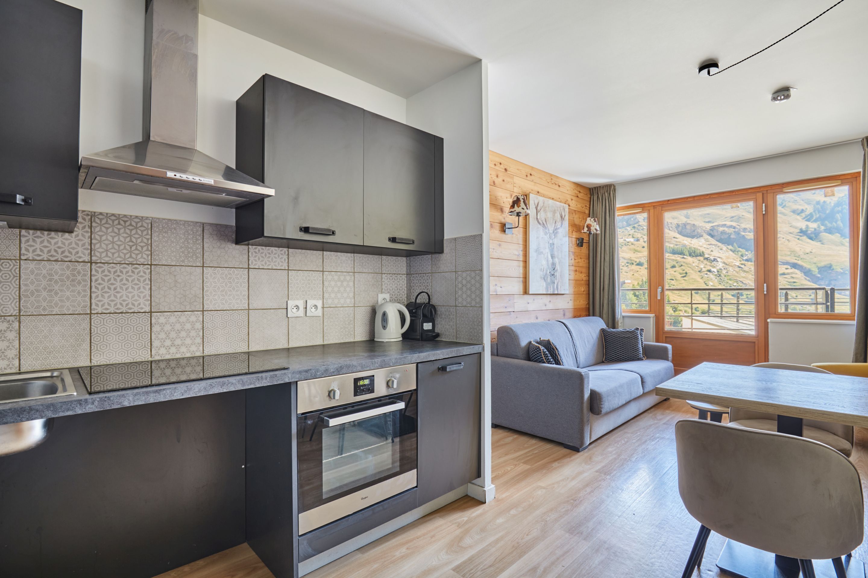 Une cuisine moderne dotée d’un four encastré et d’un coin repas avec une table et des chaises en bois.