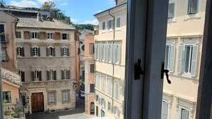 Vista de un patio flanqueado por edificios, con suelo empedrado y una puerta con picaporte.
