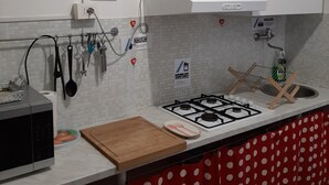 Una cocina con estufa a gas, armarios blancos, microondas y encimera con estampado de lunares rojos.