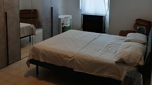Un dormitorio con una cama grande, un armario, un escritorio y una ventana con cortinas.