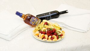 A plate of fruit and two bottles on a white textured surface. - BLUEWAY (Istanbul)