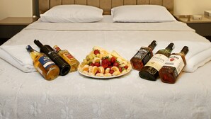 A neatly made bed with pillows, a plate of fruit, and bottles of liquor. - BLUEWAY (Istanbul)