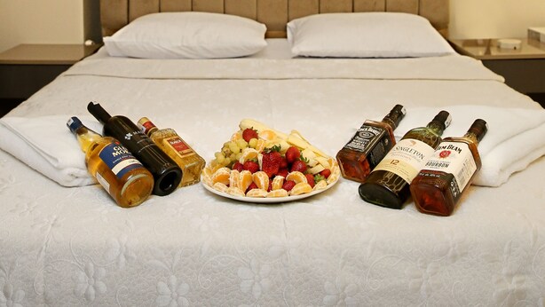 A neatly made bed with pillows, a plate of fruit, and bottles of liquor. - BLUEWAY (Istanbul)