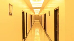 A long, well-lit hallway with doors on both sides, leading to rooms. - Eden Green (Ganaur)