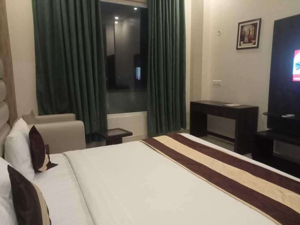 Een hotelkamer met een bed, een televisie, een bureau en een raam met gordijnen.