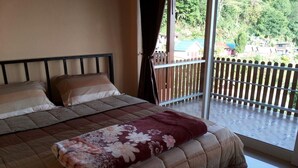 Un dormitorio con cama, ventana con vistas al exterior y balcón con barandilla de madera.