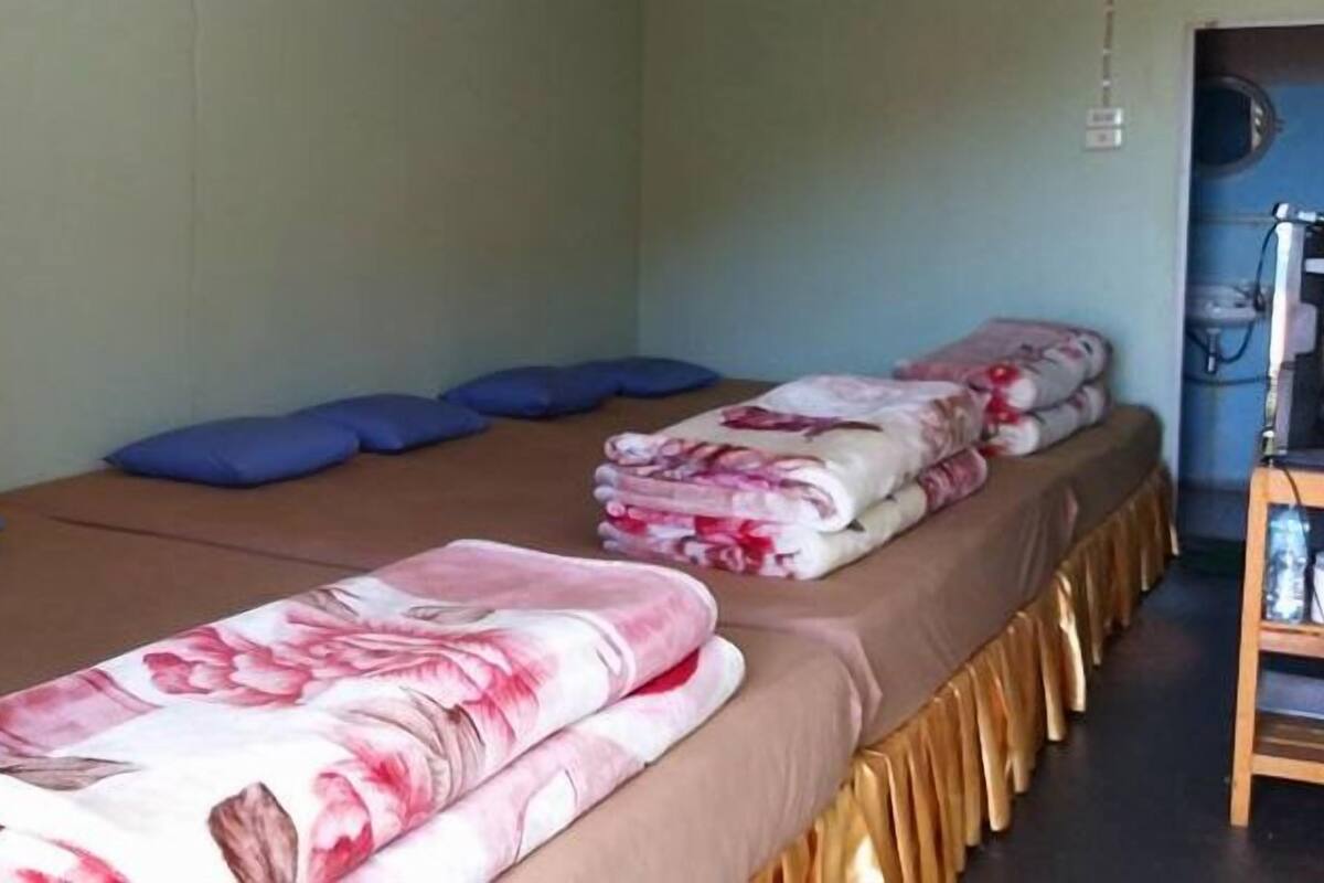 A room with two beds, each with a floral blanket and blue pillows.