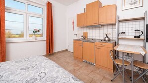 Una cocina compacta con armarios de madera, una pequeña mesa de comedor y un ventanal con cortinas.